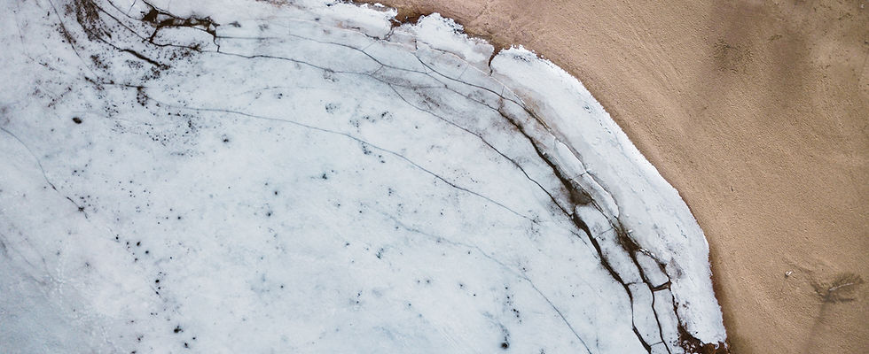 A physical transition zone in nature, where a frozen lake meets a desert shore.